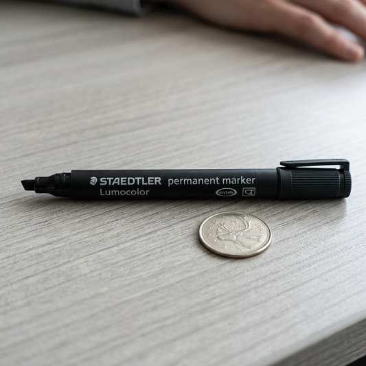 Staedtler permanent marker shown next to a common pencil and calculator for scale on a desk.