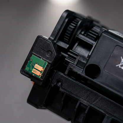 Extreme close-up of the green chip and gold contacts on the black toner cartridge end.