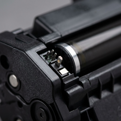 A detailed macro photograph showing the metal contact pins and textured plastic casing of the toner cartridge.