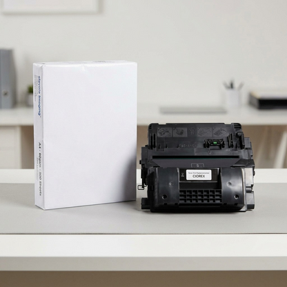 A large black laser toner cartridge is placed next to a standard ream of A4 printer paper for clear scale reference.