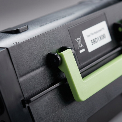 Macro close-up of a central part of the 002-06-S581X toner cartridge, showing the smooth black material, the specific light green handle structure, and the small black label (S581X00) with its regulatory logos, demonstrating precision fit and component details.