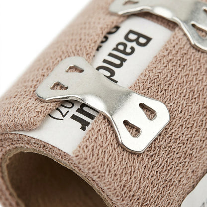 Macro photo detail of a first aid elastic bandage roll, focusing on the metal fastener clips.