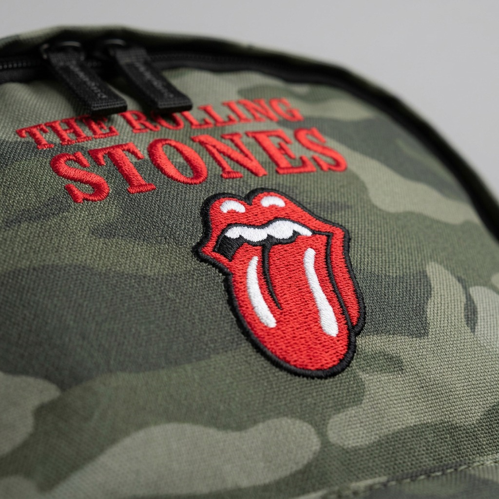 Macro detail of embroidered Rolling Stones tongue logo and "THE ROLLING STONES" text on a camo canvas the back.