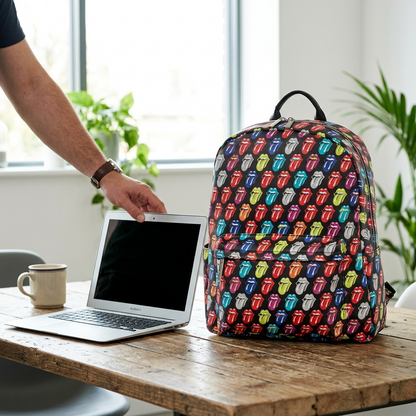 An indoor lifestyle photo showing the Rolling Stones backpack next to a 13-inch laptop and a commuter train window.
