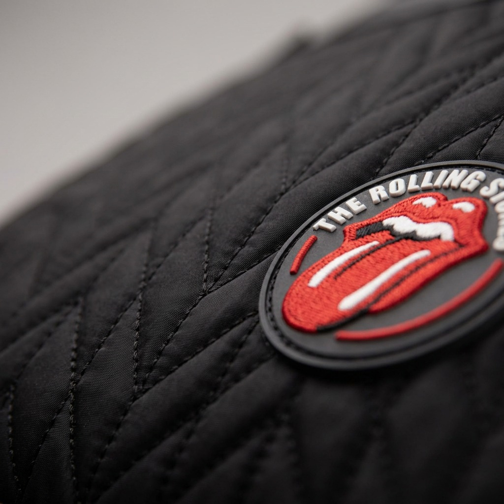 Extreme close-up shot of the The Rolling Stones tongue logo patch and quilted texture on the Bugatti backpack.