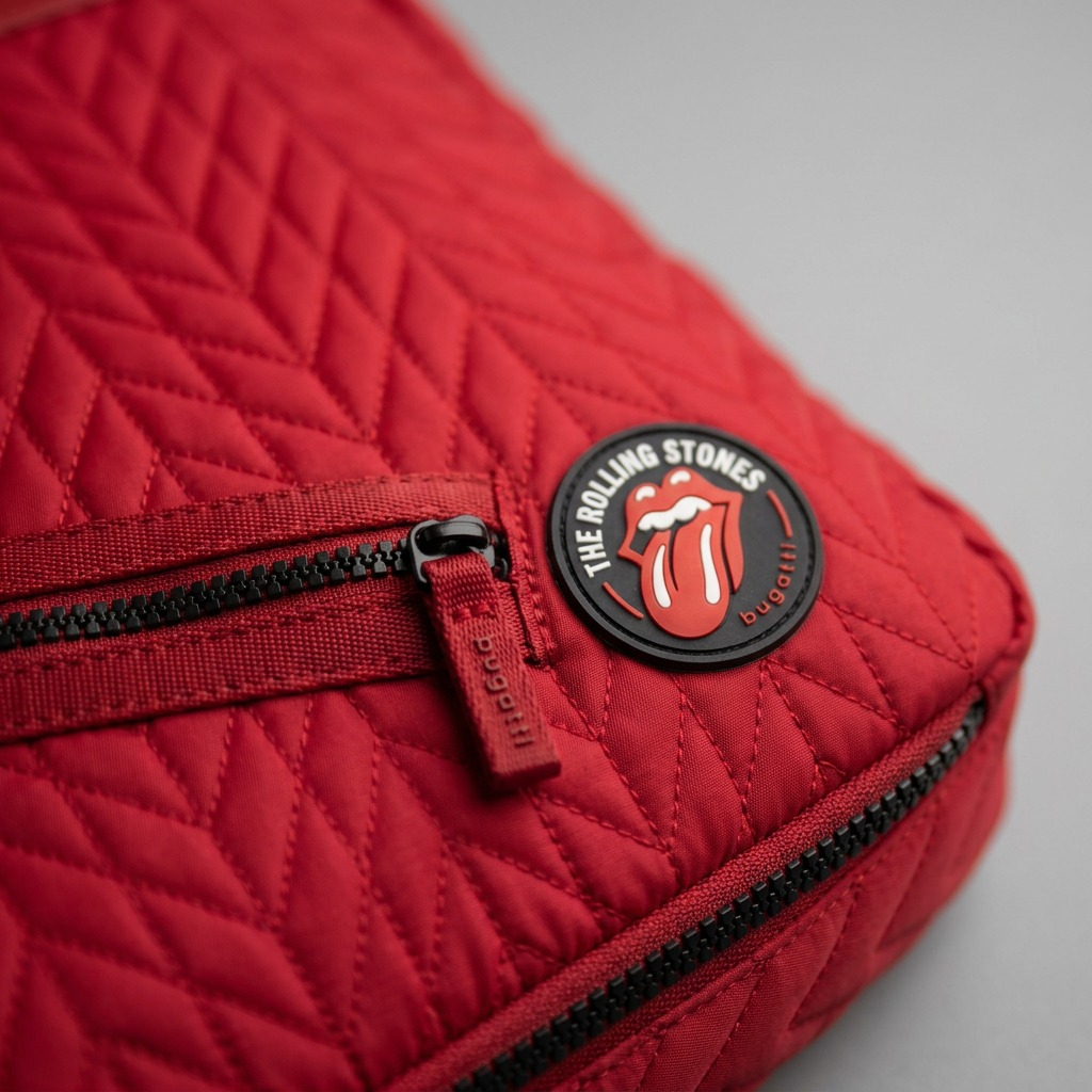 Extreme close-up of the red quilted backpack's tongue logo patch and intricate chevron stitching detail