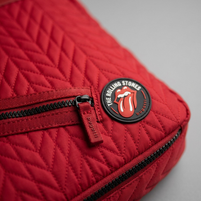 Extreme close-up of the red quilted backpack's tongue logo patch and intricate chevron stitching detail