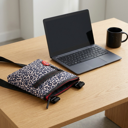 Leopard print crossbody bag with Rolling Stones branding on a desk next to an open laptop and mug.
