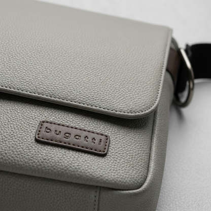 An extreme close-up view of the fine pebble grain leather and metal strap clasp on the Bugatti messenger bag.