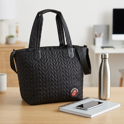 An e-commerce studio shot comparing the black quilted The Rolling Stones tote bag to the standard size of an A4 notebook and reusable water bottle, showing its real-world dimensions.