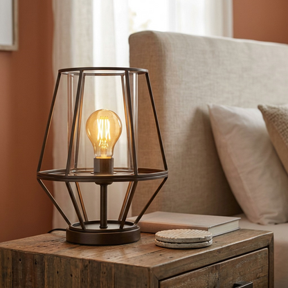 The SYLVANIA Sylvania SMART+ Wi-Fi Filament Amber A19 LED bulb installed in a modern table lamp on a rustic bedside table.