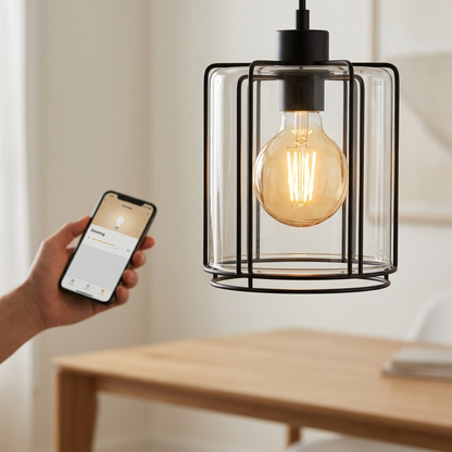 Lifestyle image showing the clear glass Sylvania G25 SMART+ WiFi filament bulb with warm glow in a pendant fixture.