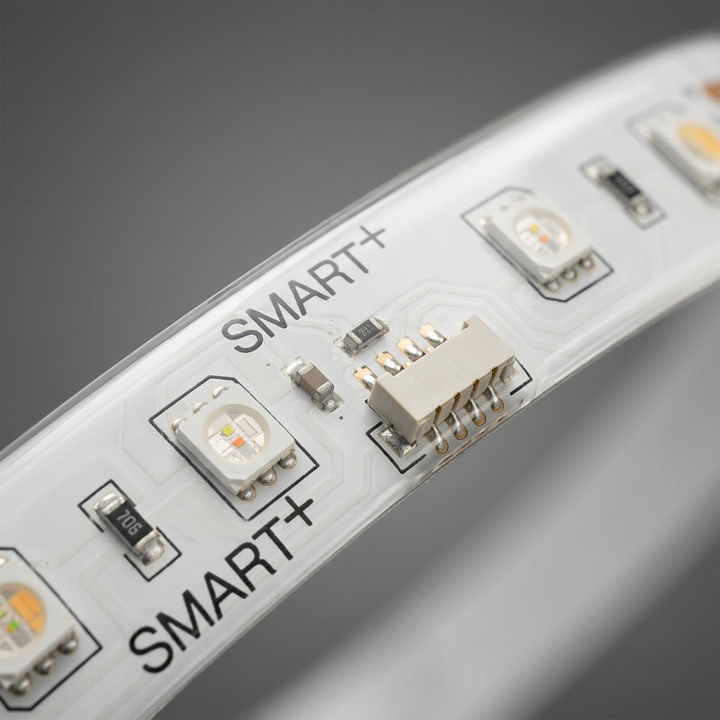 Macro photo detail of the flexible LED strip's clear silicone coating, integrated color and white LEDs, printed "SMART+" text, and internal gold connection pads.