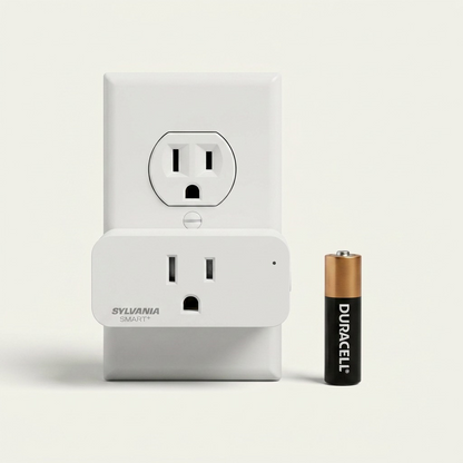 Visual scale reference showing the small Sylvania SMART+ smart plug positioned beside a single AA battery on a light wood desk surface.
