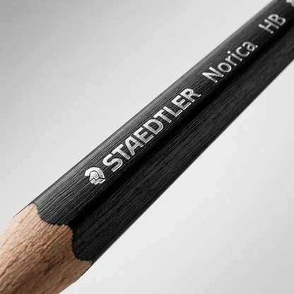 Macro close-up of a STAEDTLER Norica black HB pencil, focusing on its detailed branding and textured barrel.