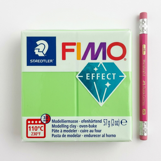 Fimo Lime Green Effect clay block, shown next to a sharp generic wooden pencil on a desk.