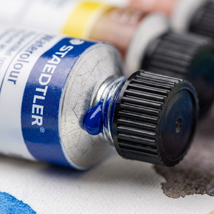 Extreme macro close-up of a Staedtler tube: cap, crimped label, and extruded paint texture.