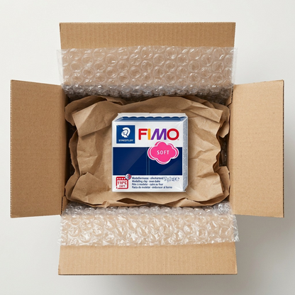 Premium unboxing scene showing open box, bubble wrap, and a perfect Fimo Windsor Blue clay block within plastic retail wrap.