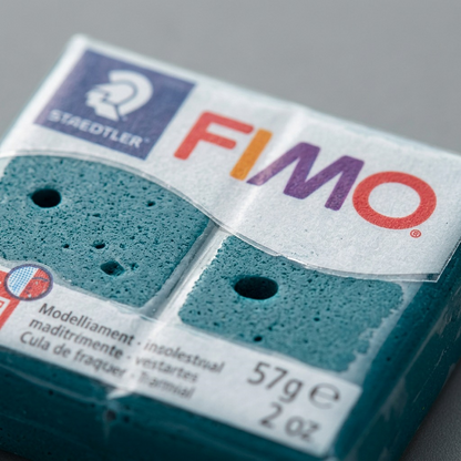 Extreme macro detail of the STAEDTLER FIMO Professional Petrol clay texture and brand print.