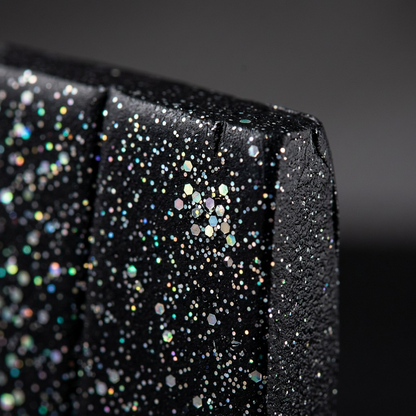 Extreme macro view of deep black Fimo Stardust clay, revealing embedded holographic glitter.