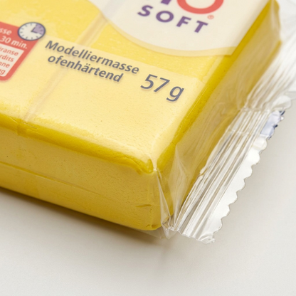 Extreme close-up of a 57g lemon yellow STAEDTLER FIMO Soft clay block in its plastic packaging.