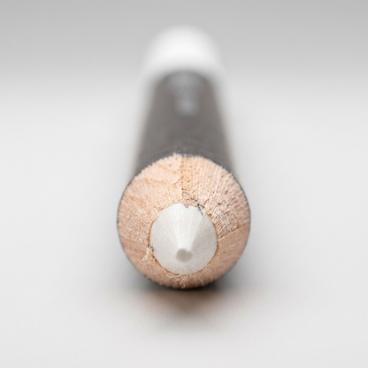 A detailed macro photograph showing the precise sharpened point and natural wood core of the White STAEDTLER Lumocolor permanent glasochrom marker.