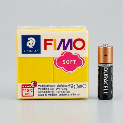 The STAEDTLER Fimo Soft clay packet is placed next to a realistic AA battery for scale.