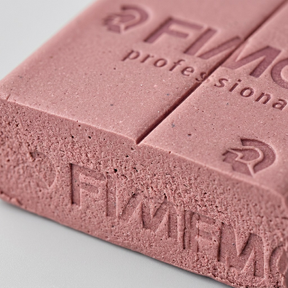 A detailed macro shot showing the fine grain and embossed text on a dusty pink Fimo professional clay block.