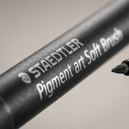 Extreme macro detail of a STAEDTLER Pigment arts Soft Brush gray barrel, showing fine plastic texture and printed text.