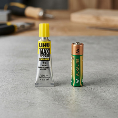 UHU Max Repair Extreme adhesive tube, with its canonical labels, next to a standard AA battery.