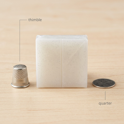 A close-up photograph comparing the Fimo Effect Translucent clay block (image\_0.png) with a standard metal sewing thimble, demonstrating its small, 2-ounce size on a work desk.