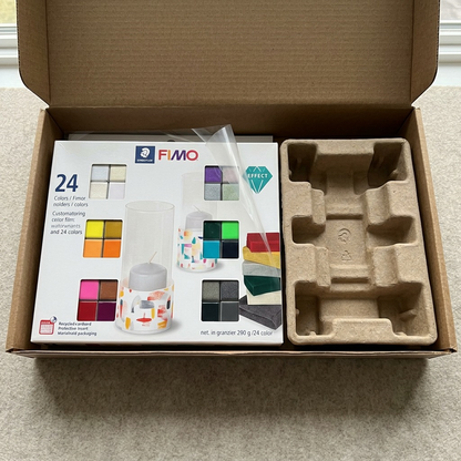 A premium close-up photo shows the Fimo Effect set packaging, safely nestled within specialized protective padding in an open delivery box.