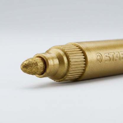 A close-up photograph of the fiber tip on a STAEDTLER metallic maker with ink visible on a surface.