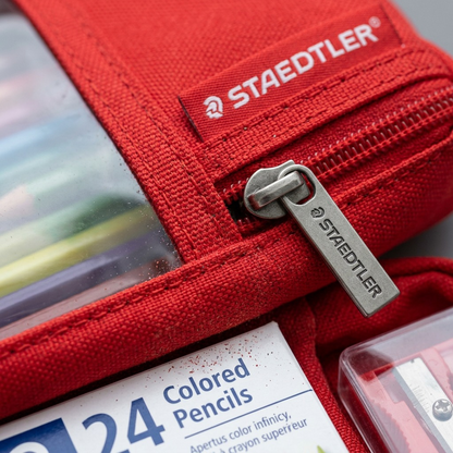 Macro photograph capturing the fine texture of the red canvas pencil case fabric, a clean metal zipper pull, and crisply printed STAEDTLER logo.