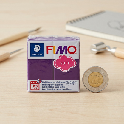 A 3/4 view photograph of the Fimo Soft Plum block next to a standard Canadian 2-dollar coin and a mechanical pencil.