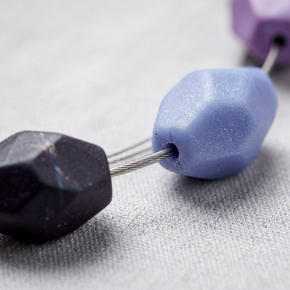 Macro close-up of STAEDTLER FIMO glam color beads, showcasing their complex faceted geometry and matte texture.