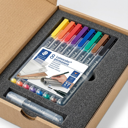 A premium unboxing view of the STAEDTLER Lumocolor set, nestled in form-fitting foam padding for protection.