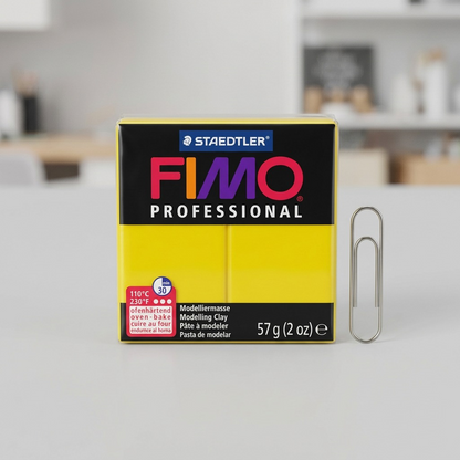 A product-led image showing the yellow Fimo Professional block next to a classic metal paperclip for scale, on a clean desk.