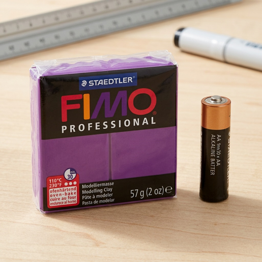 A standard package of Staedtler Fimo Professional solid-purple clay, showing its real-world scale alongside an ordinary, widely recognized AA battery on a light wooden table.