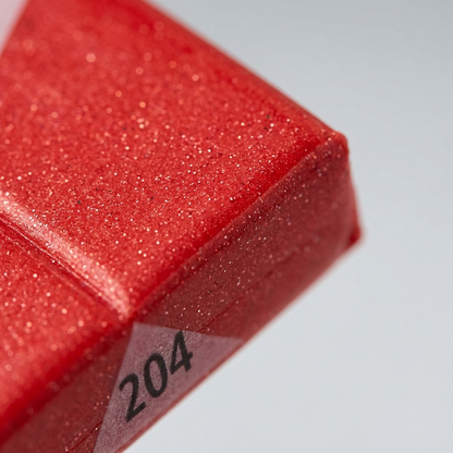 Macro detail shot of the FIMO EFFECT texture, showing specific, small metallic-gold glitter specks embedded within the red polymer clay block, which is the defining 'Effect'.