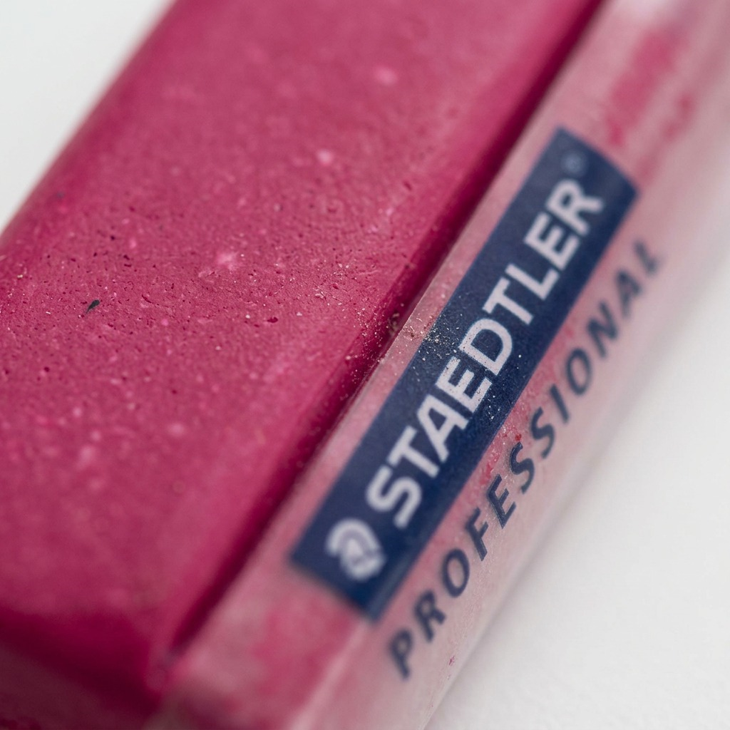 A detailed macro photograph showing the tactile texture of STAEDTLER FIMO Professional Magenta modelling clay, highlighting its fine grain and firm consistency. The sharp print and bold colors of the branding can be seen in the background.