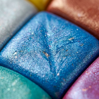 Macro view focusing on the fine, iridescent pigment dust and texture of a blue pearl Fimo Effect clay block.