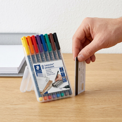 A high-angle photograph showing a hand next to the STAEDTLER permanent marker set.
