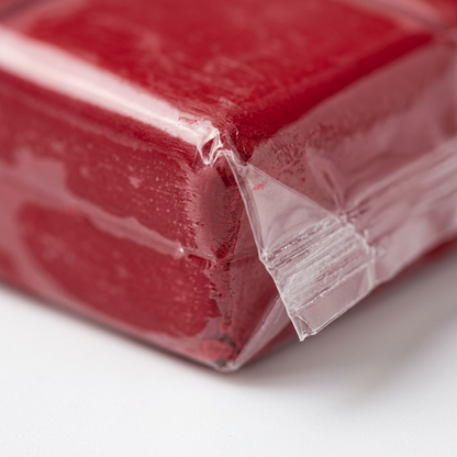 Extreme macro photo showing the rich cherry red color of Fimo Soft clay through the texture of its plastic wrap.