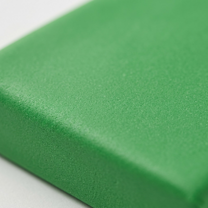 Extreme macro view of the vivid Fimo Soft matte green clay block texture, showing its uniform, fine-grained surface.