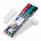 A high-resolution photo of four STAEDTLER permanent markers (red, blue, green, black) in a clear plastic case.