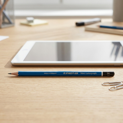 Scale reference photo for a Staedtler Mars Lumograph 3H pencil on a desk.