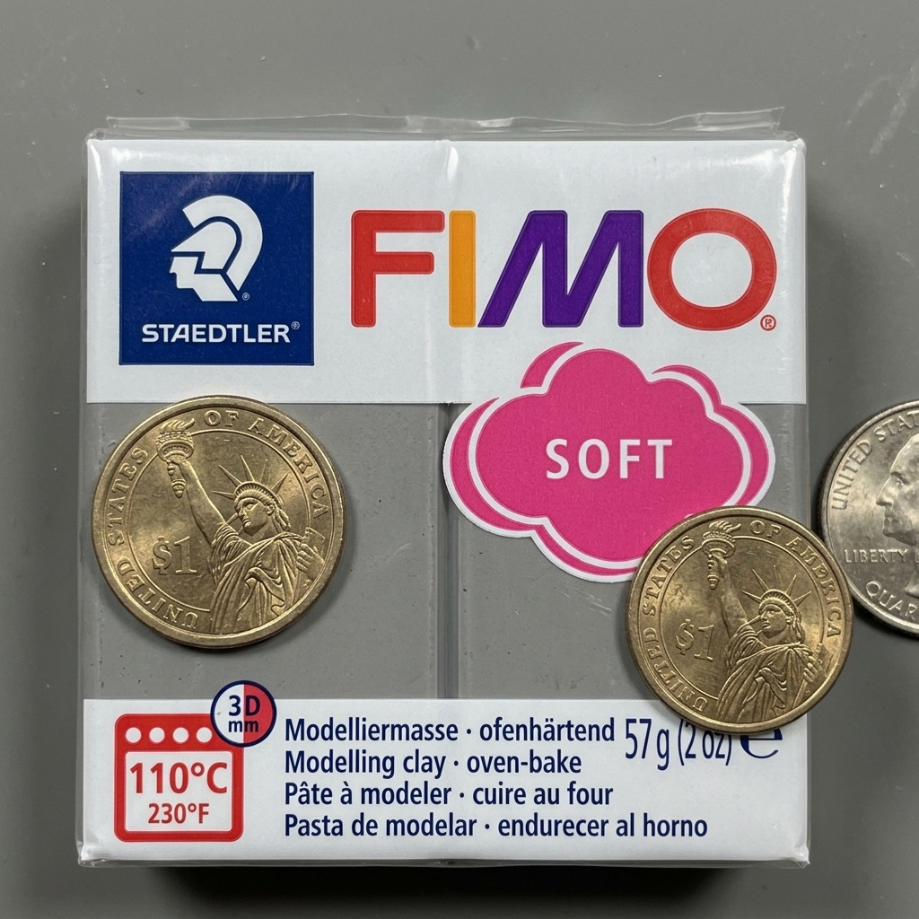 A 57g pack of grey Fimo Soft clay next to a dollar coin for accurate size reference.