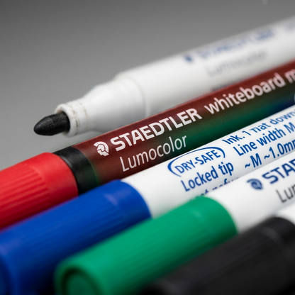 Extreme macro-view focusing on the four Staedtler 301.WP4 marker tips (Red, Blue, Green, Black) and the detailed barrel printing, showing the "M" nib specification and ink properties on the clean plastic surfaces.