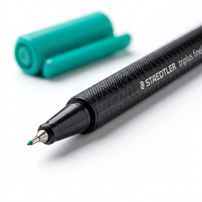 A macro photograph detailing the fine fineliner tip, knurled grip texture, and printed branding of the Staedtler pen.
